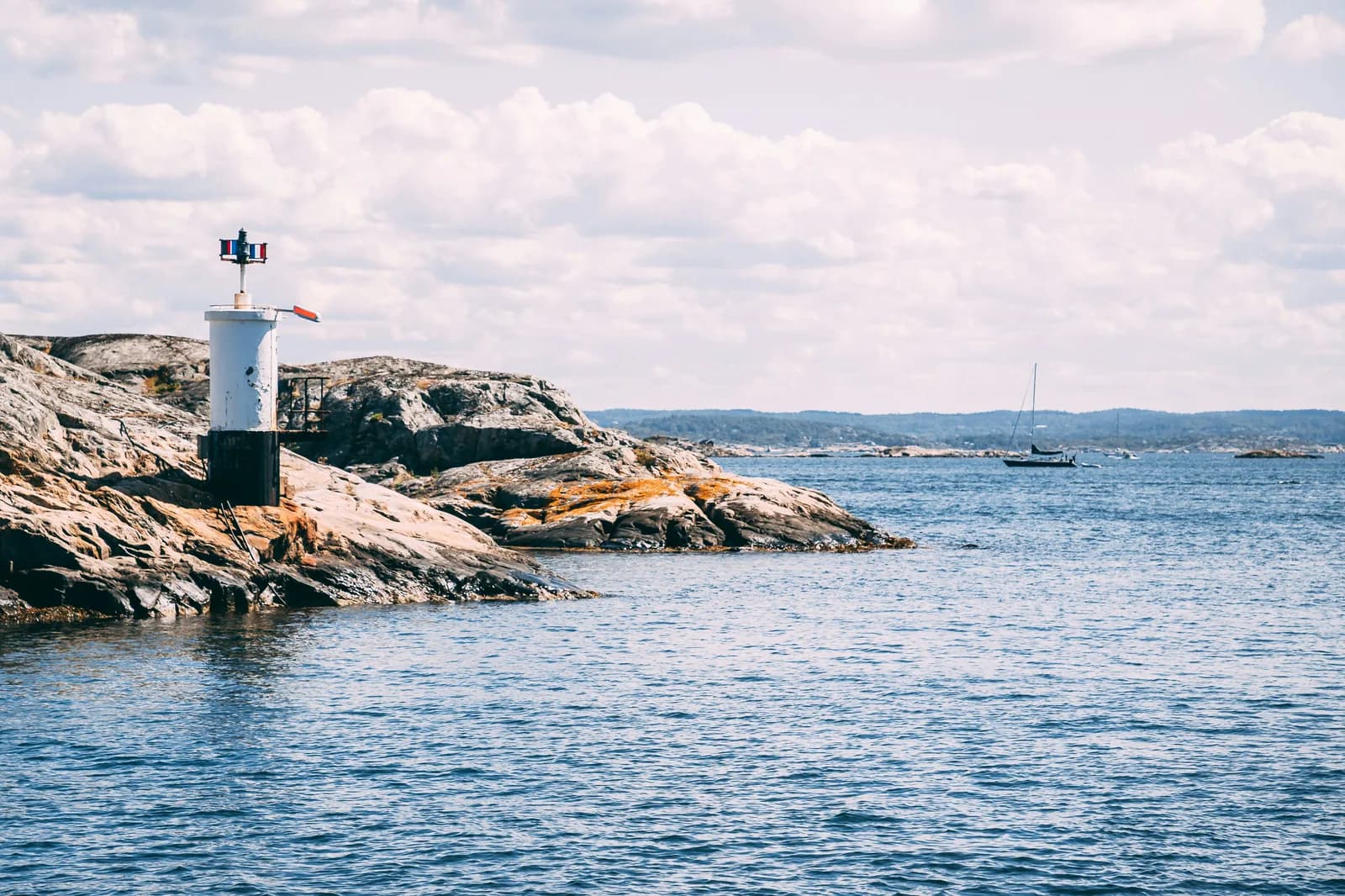 A navigation beacon on a sun-warmed rocky skerry in the Gothenburg archipelago, the open Skagerrak beyond.